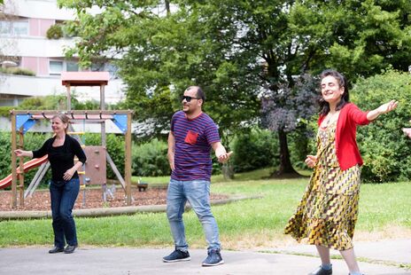 Drei BewohnerInnen beim Zumba-tanzen im Hof einer Wohnhausanlage
