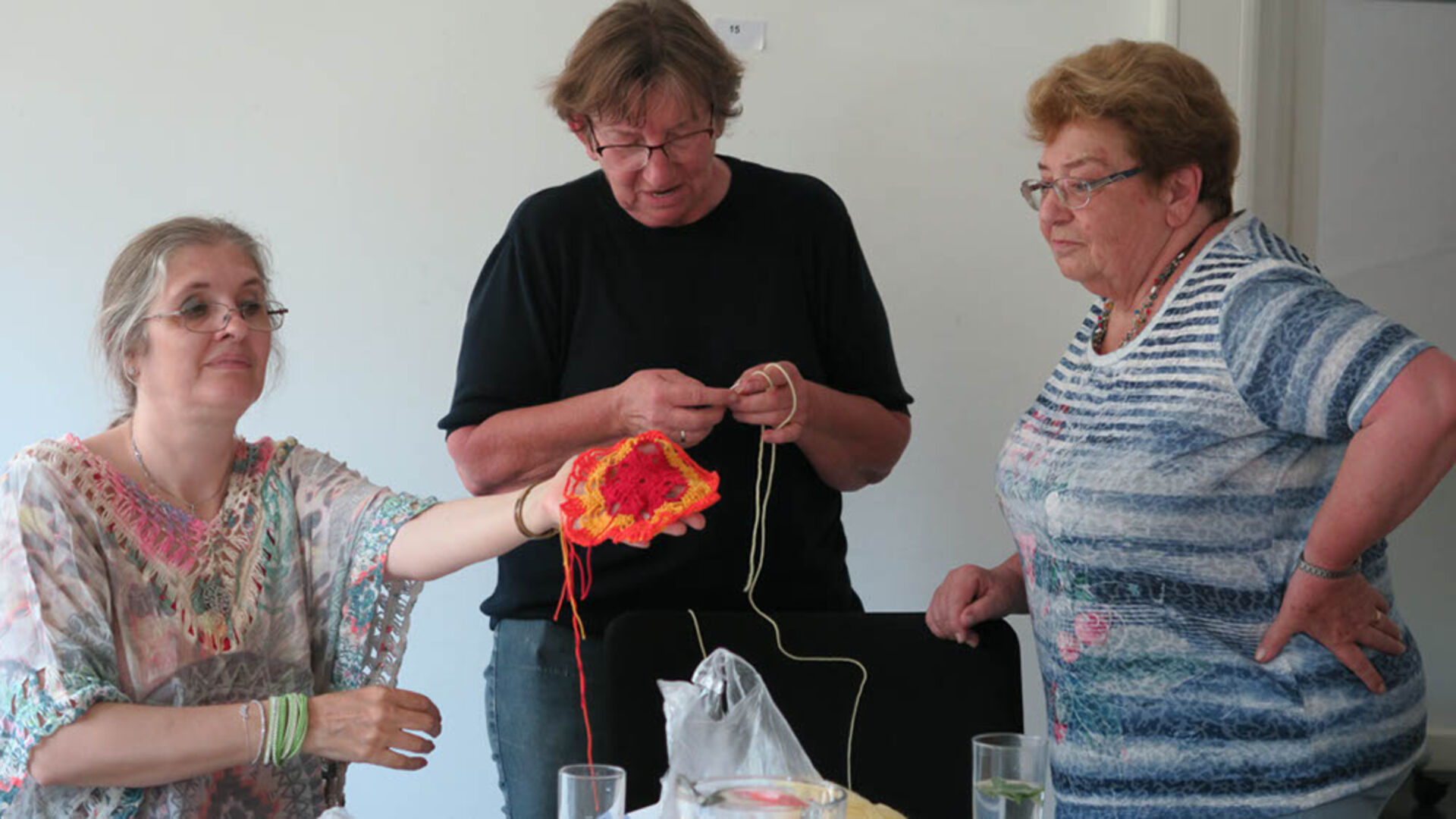 Einige Besucherinnen der Kreativwerkstatt häkeln.