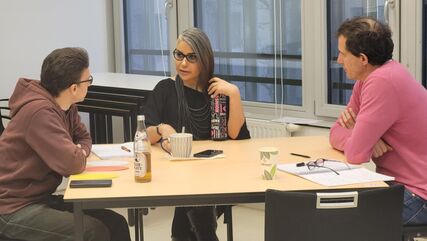 drei Personen im Gespräch, an einem Tisch sitzend. Schulungssituation/Gruppenarbeit