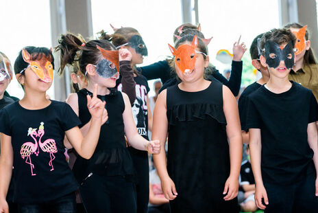 Kinder mit Gesichtsmasken zeigen, was sie bei der Peer-Meditation gelernt haben.