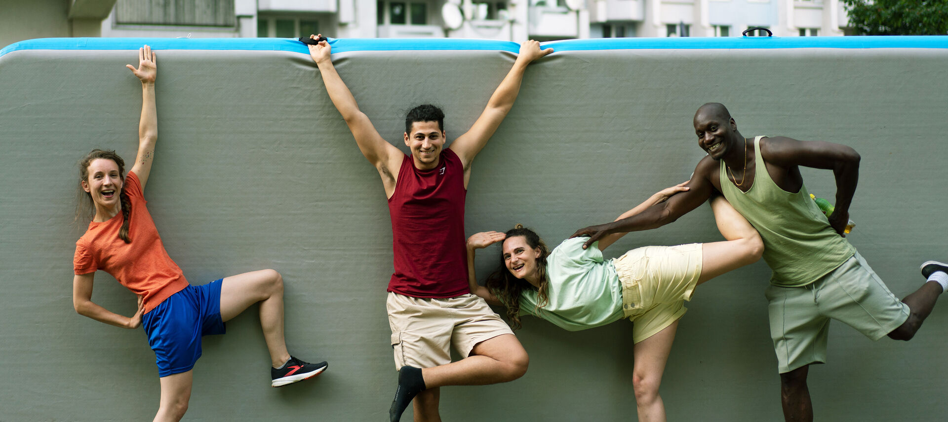 Vier Tänzer*innen von The Here & Now Collective posieren vor einer grauen Wand