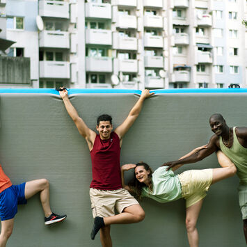 Vier Tänzer*innen von The Here & Now Collective posieren vor einer grauen Wand