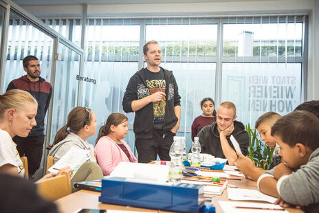 Kinder hören gespannt dem Graffiti Workshop Leiter zu.