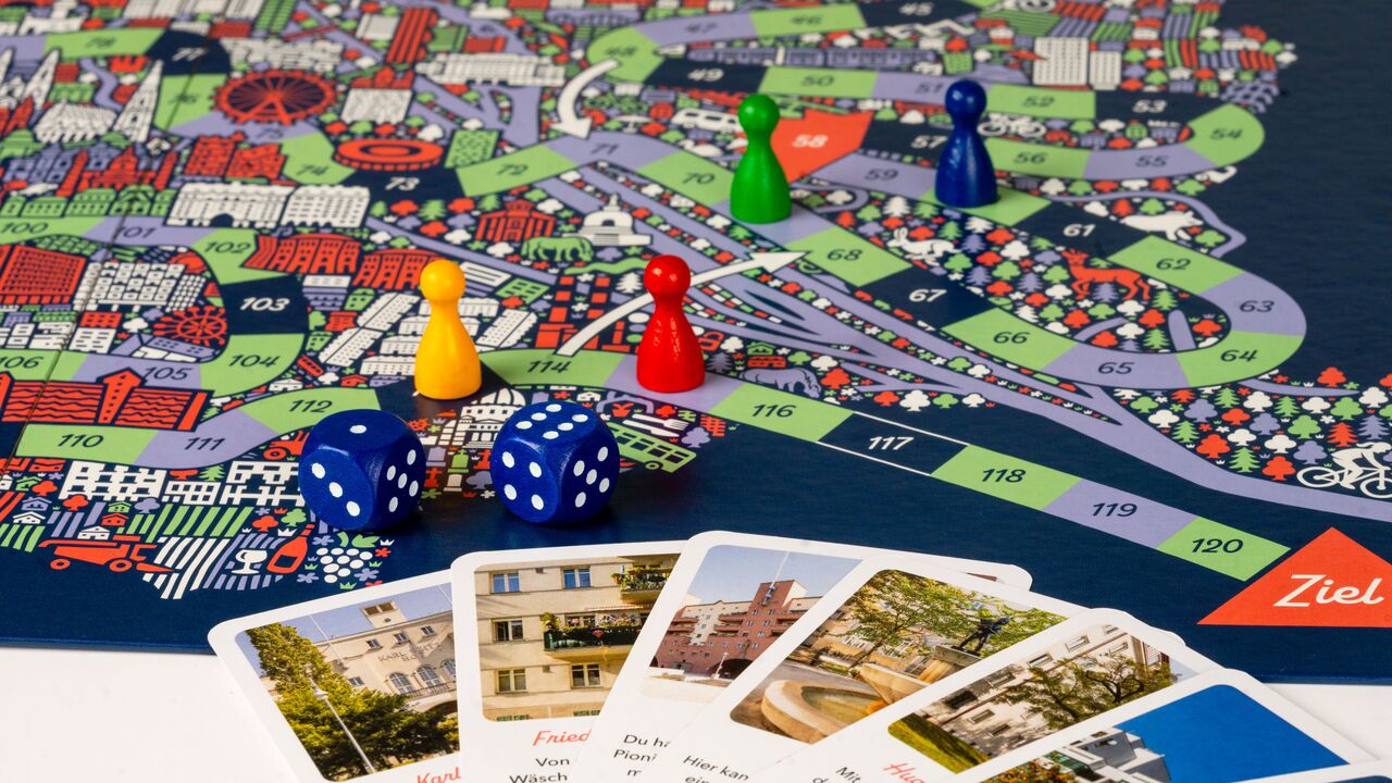 Brettspiel mit Spielfiguren, Würfeln, einem Stadtplan von Wien und Spielkarten mit Fotos von Wiener Gemeindebauten